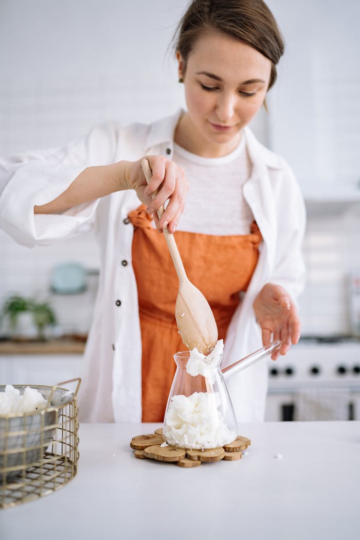 A young woman making a handmade soy candle in a cozy indoor setting, showcasing creativity and craftsmanship.